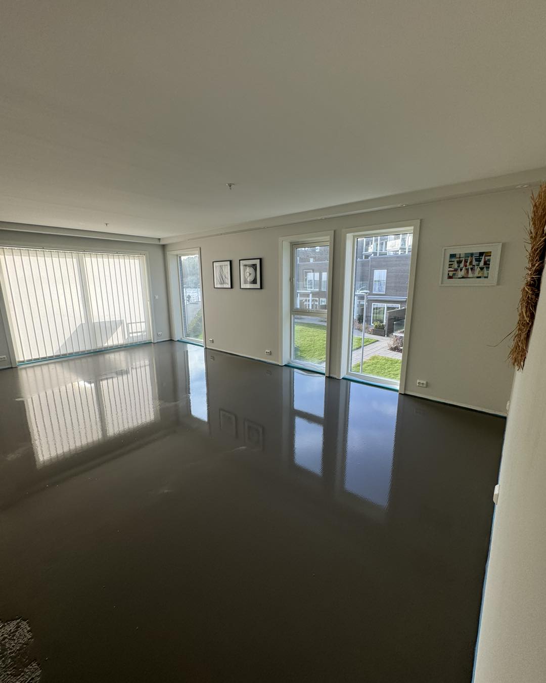 Stue med nylagt glanset gulv og store vinduer med dagslys