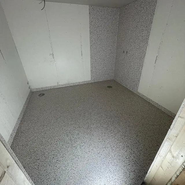 Rom med hvite vegger og terrazzo-gulv under oppussing